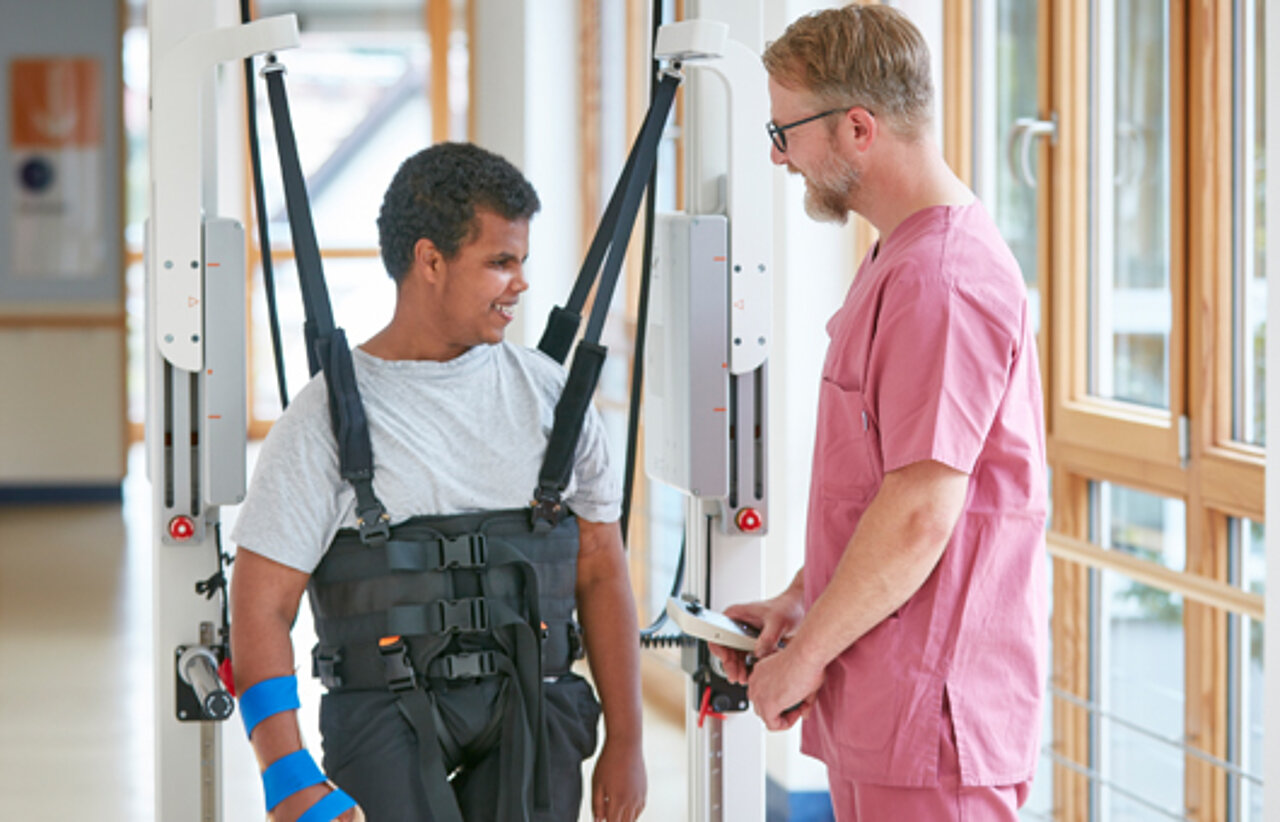 Therapeutische Schwerpunkte der Kinderklinik Schömberg  Bild: Ein Therapeut und ein Patient beim Gangtraining im Innowalk. Das Bild ist verlinkt mit der Rubrik Therapeutische Schwerpunkte